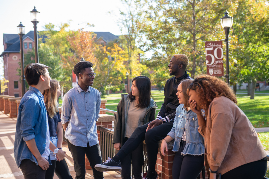 A group of students laughing on a summer day on campus