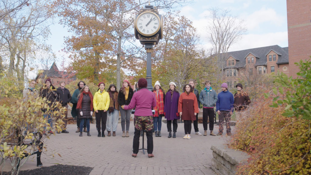 The UPEI Chamber Singers A group of male and female students are singing outdoors on campus