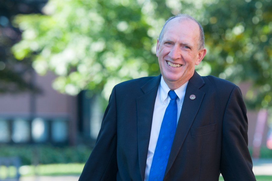 A smiling older man in a dark suit