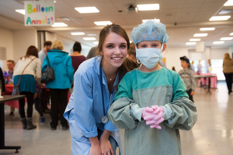 An AVC student helps an attendee get gowned and gloved like a surgeon.