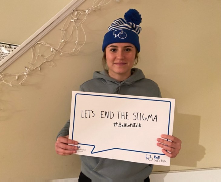 photo of young woman wearing toque and holding thought bubble placard