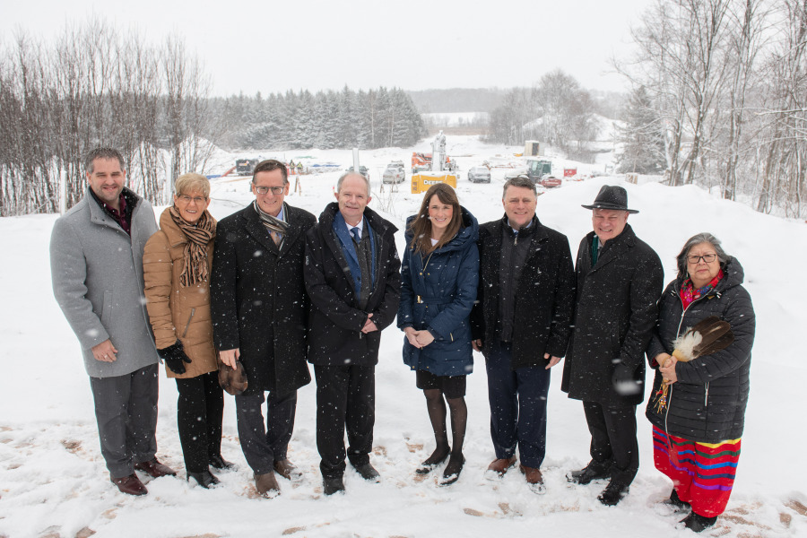 photo of 8 people standing side by side in front of construction site