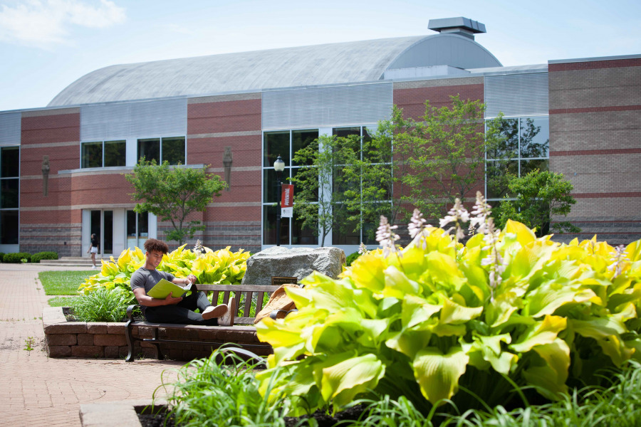 photo of student in front of modern brick building