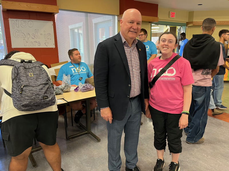 Man and woman standing in front of tables set up for student check-in