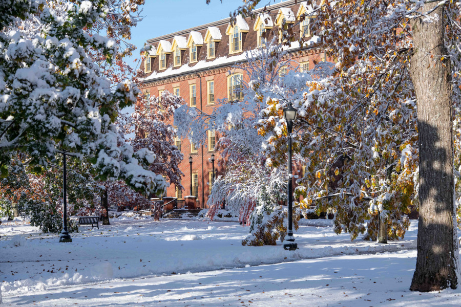 photo of brick building on campus with snow covered trees and foreground