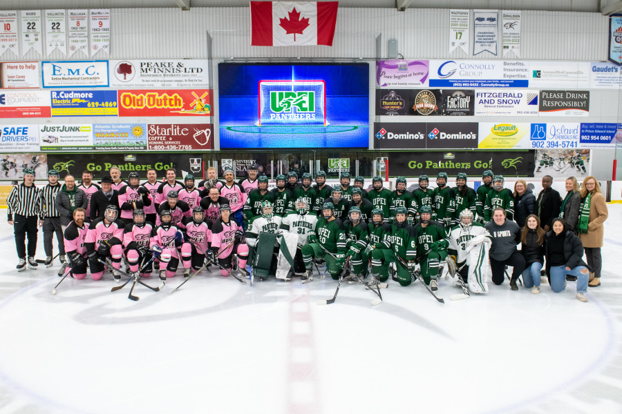 The UPEI faculty-staff team and the UPEI Women’s Hockey Panthers pose for a photo with their coaches and referees