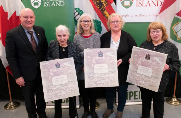 photo of of five people standing holding three plaques