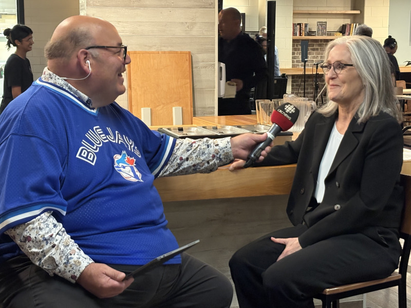 Man holding a microphone while interviewing a woman 