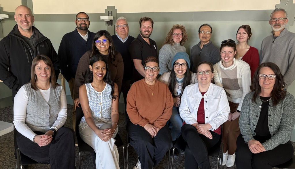 Photo of large group of people, some standing and others sitting
