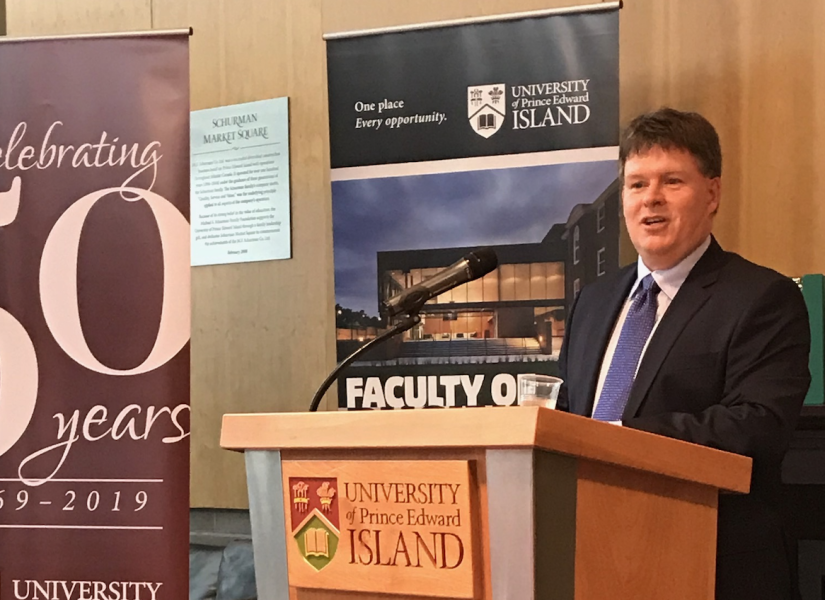 photo of man speaking at a podium flanked by pull up banners