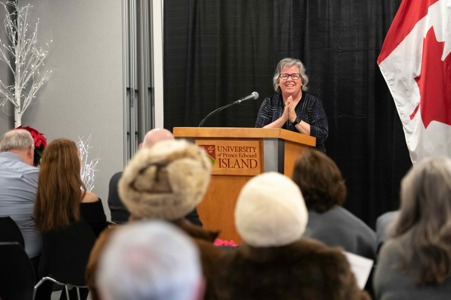 Woman standing at podium with hands clasped