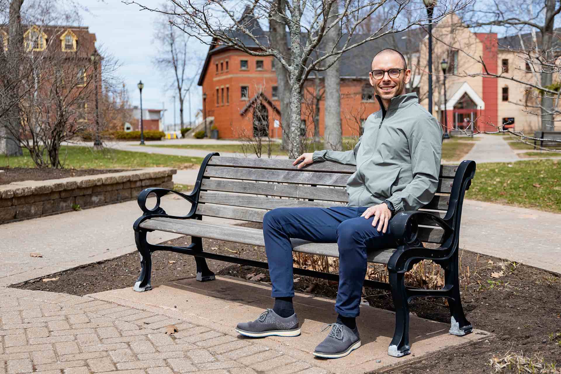 Peter Blanchard sitting on a bench in UPEI's quad