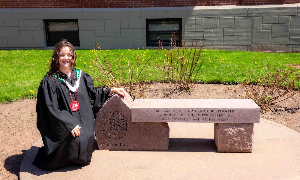 UPEI student Annika Masters beside Mi'kmaq commemorative bench