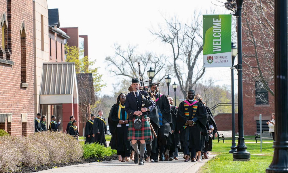 a bagpiper leading a procession of UPEI graduates