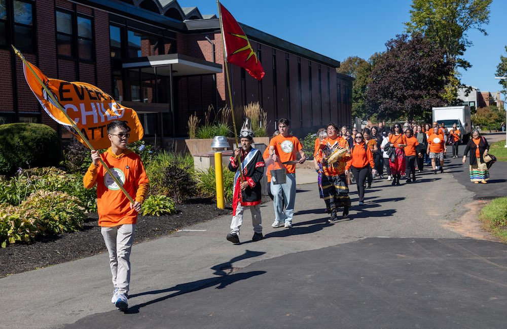 a large group of people wearing orange walking in front of Kelley Memorial Building