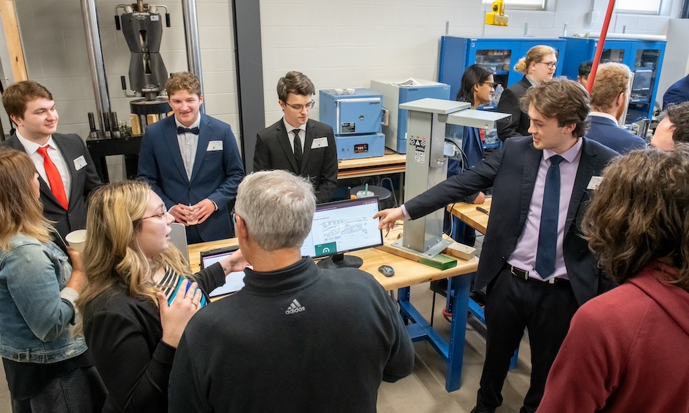 five engineering students demonstrating their project to members of the public