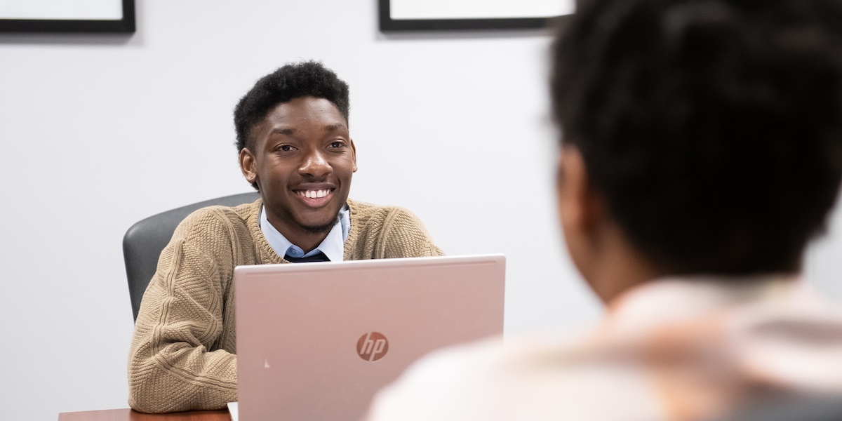 UPEI student Joshua Symonette talking with a client in an office