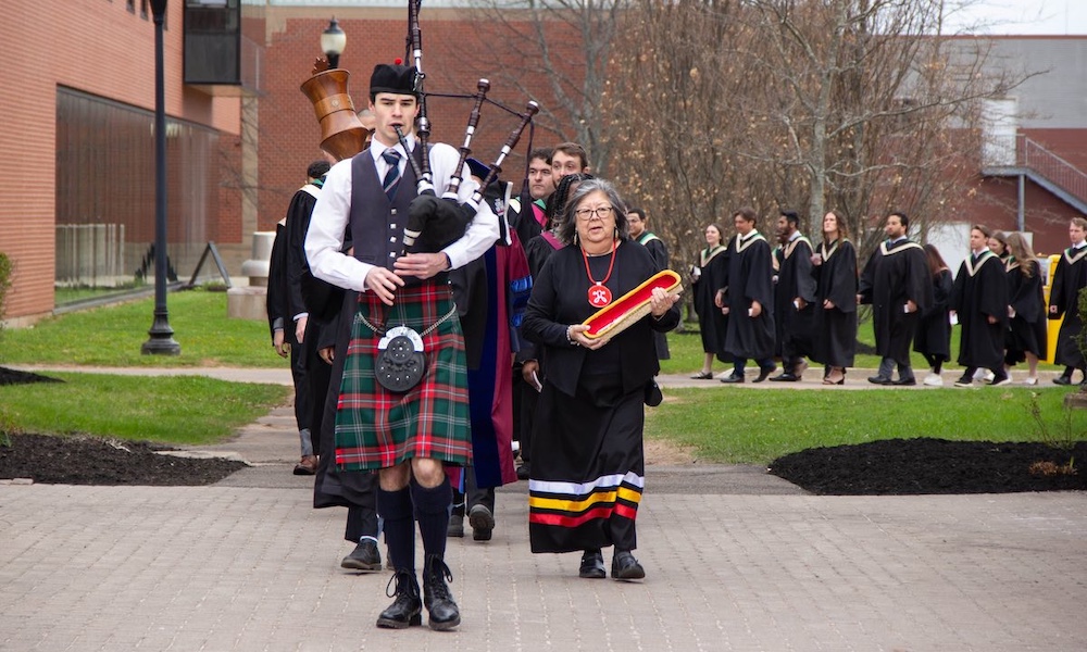 Elder Judy Clark carrying the Eagle Feather at Convocation