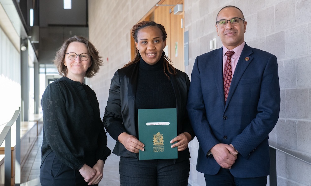 Patience Adaobor accepting an award from two professors