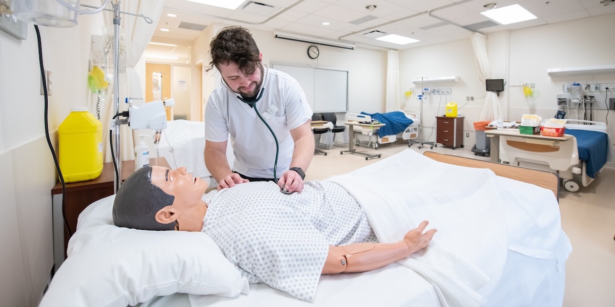 upei nursing graduate mitchell bingley working with a patient in the nursing lab