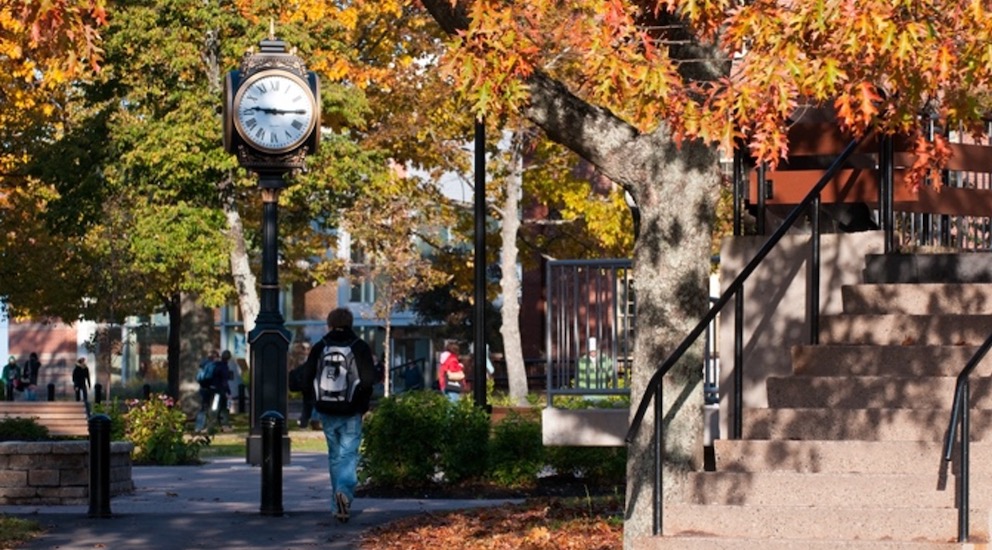 student walking past the clock in UPEI's quad in all 