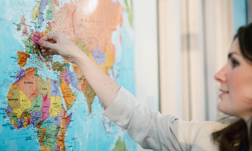 a person adding coloured pins to a map of Europe