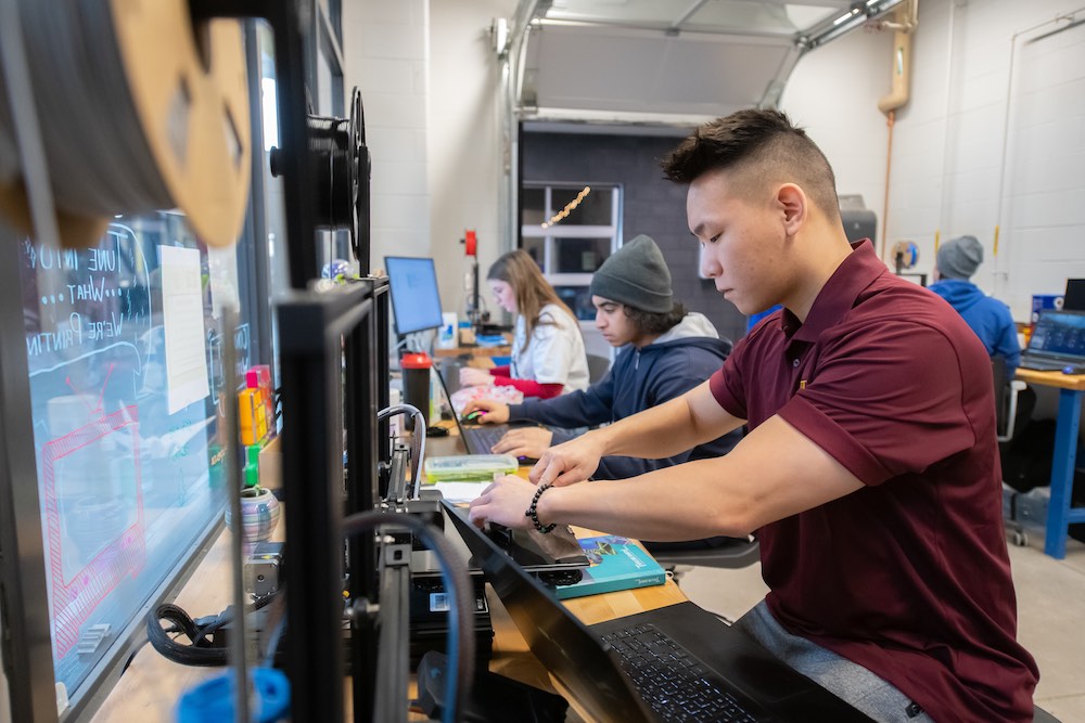 an engineering student working at a 3D printer