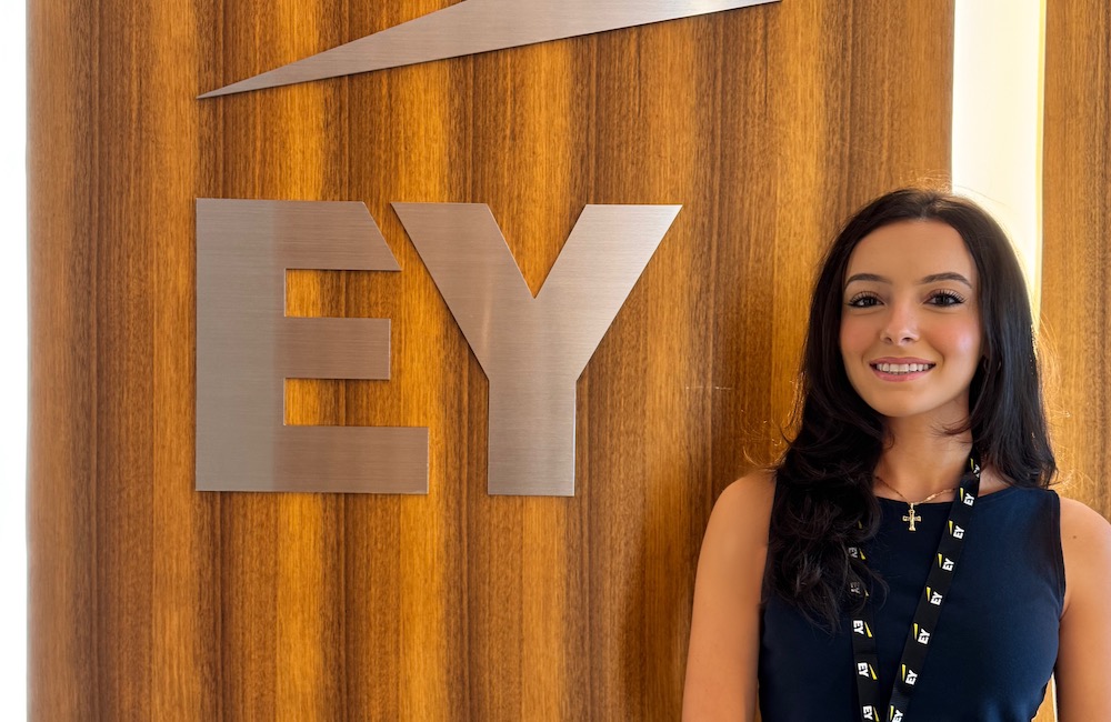 Charlize Sahely beside an EY Ernst and Young sign