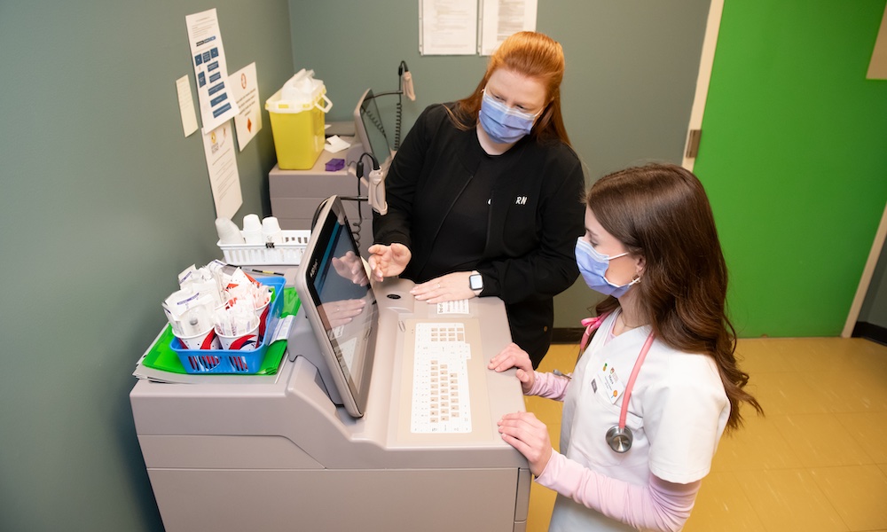 UPEI nursing student Maya White and a colleague using a computer at the Queen Elizabeth Hospital