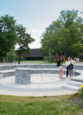 Photo of three students standing in an outdoor amphitheatre on campus