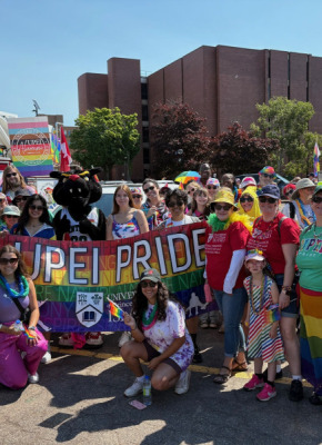 Group of people wearing colourful clothing and carrying Pride