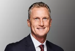 A close-up photo of a smiling man in a suit