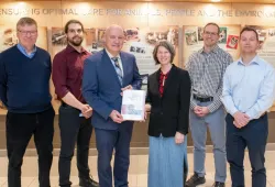 Dr. Michelle Evason presents a copy of Infectious Diseases of the Dog and Cat: A Color Handbook to Dean Greg Keefe while other contributors from AVC look on.