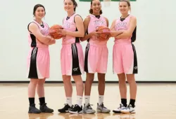 Four female basketball players in pink uniforms