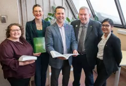 Five smiling people in a library