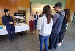 A male and female student speak with a group of students