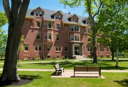 A four-storey brick building with lush trees around it