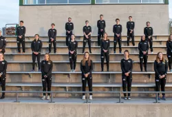 A group of male and female student athletes standing in formation on a set of bleacher seats