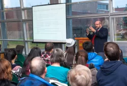 Man presenting to an audience using a projection screen