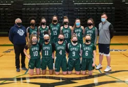 Photo of women's basketball team standing with coaches in the gym