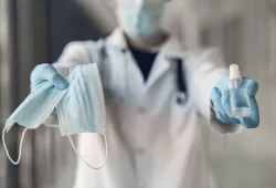 Photo of person holding masks and sanitizer