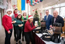 photo of students and music professor wearing Santa hats with the vice-president and president of the University