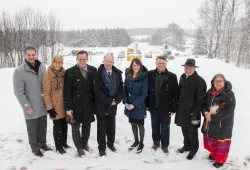 photo of 8 people standing side by side in front of construction site