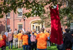 Photo of people standing in the quad listening to a speaker and wearing orange for National Day for Truth and Reconciliation watching 