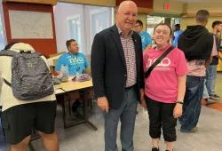 Man and woman standing in front of tables set up for student check-in