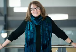 photo of woman wearing glasses leaning against a railing