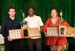 photo of three people holding large trophies