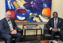 Two men sitting in arm chairs in front of a brightly coloured painting