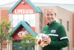 Photo of woman holding soccer ball standing in front of sports centre