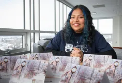 Prisha Halder, senior residence life advisor at UPEI, with a display of holiday cards featuring the campus in winter.